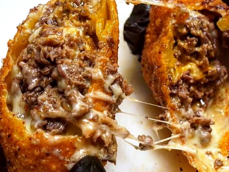 Cheesesteak egg rolls pulled apart with a long cheese pull