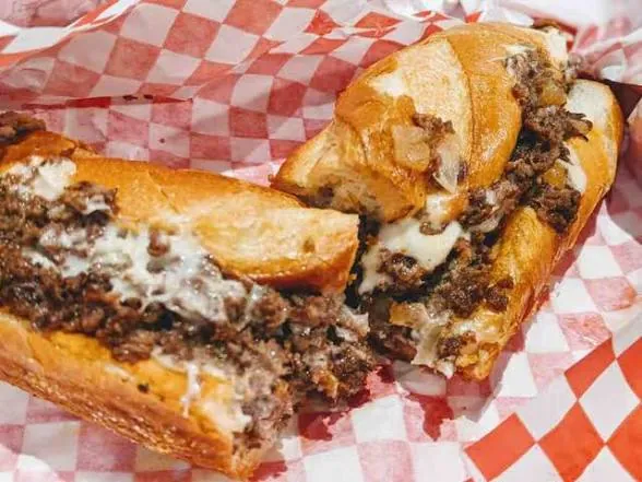A Deezy's cheesesteak cut in half on checkered paper