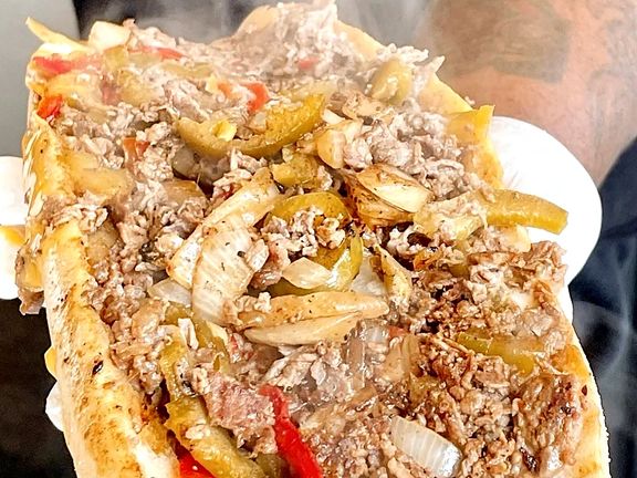 A Deezy's cheesesteak with peppers and fried onions, steaming fresh off the grill