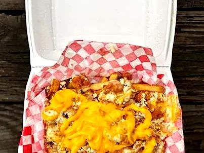 Fresh-cut fries loaded with cheese in a takeout box